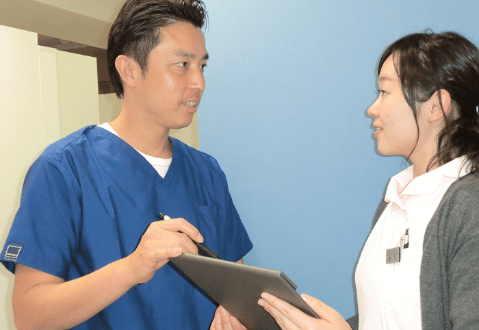 セブンデンタルクリニック院内写真｜コミュニケーションをとる吉川院長とスタッフ